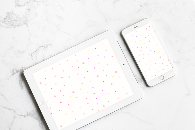 Marble background with an ipad and iphone on top displaying Watercolor Hearts Valentine's Day Wallpaper Downloads