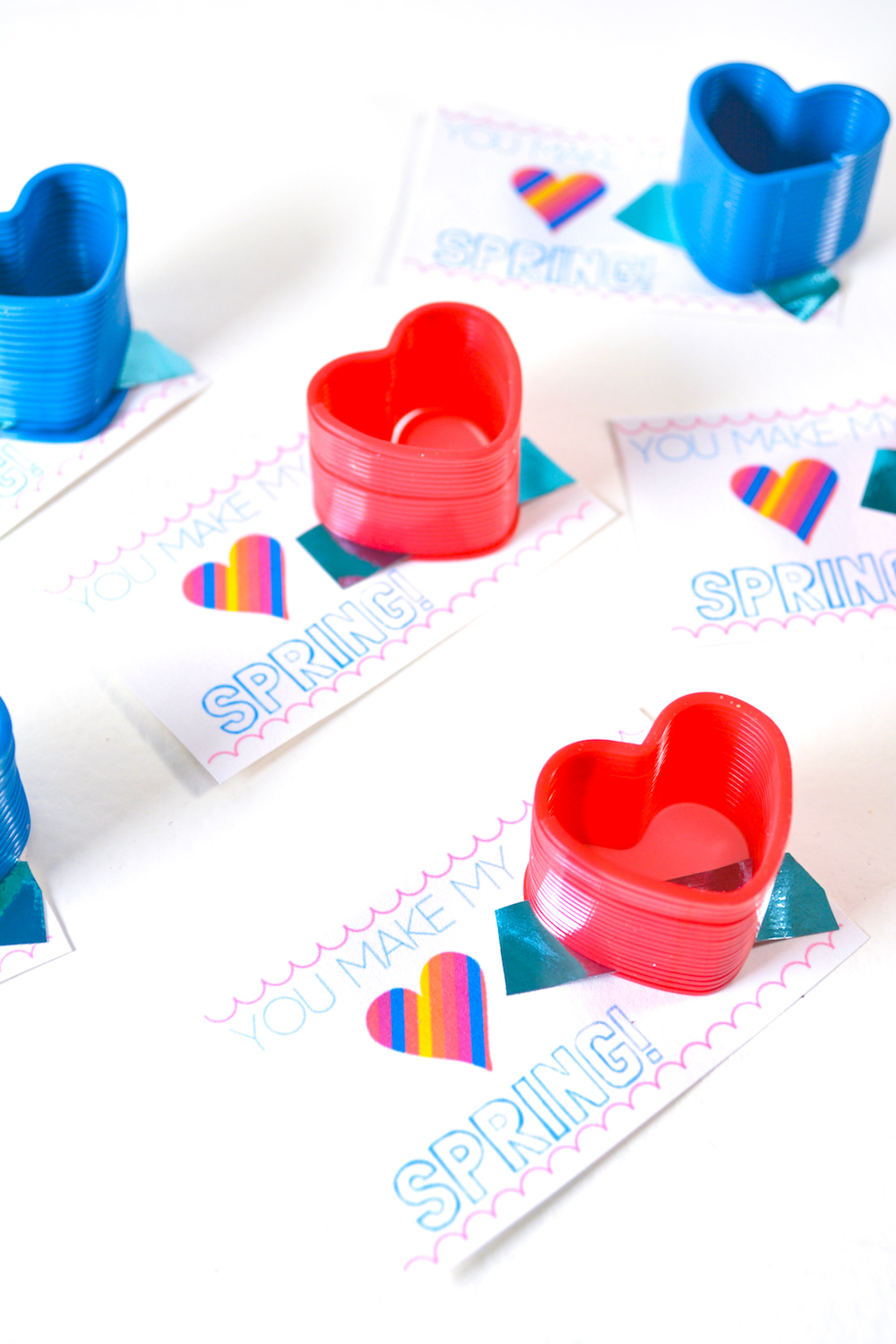 White background with valentines with red and blue slinkies attached