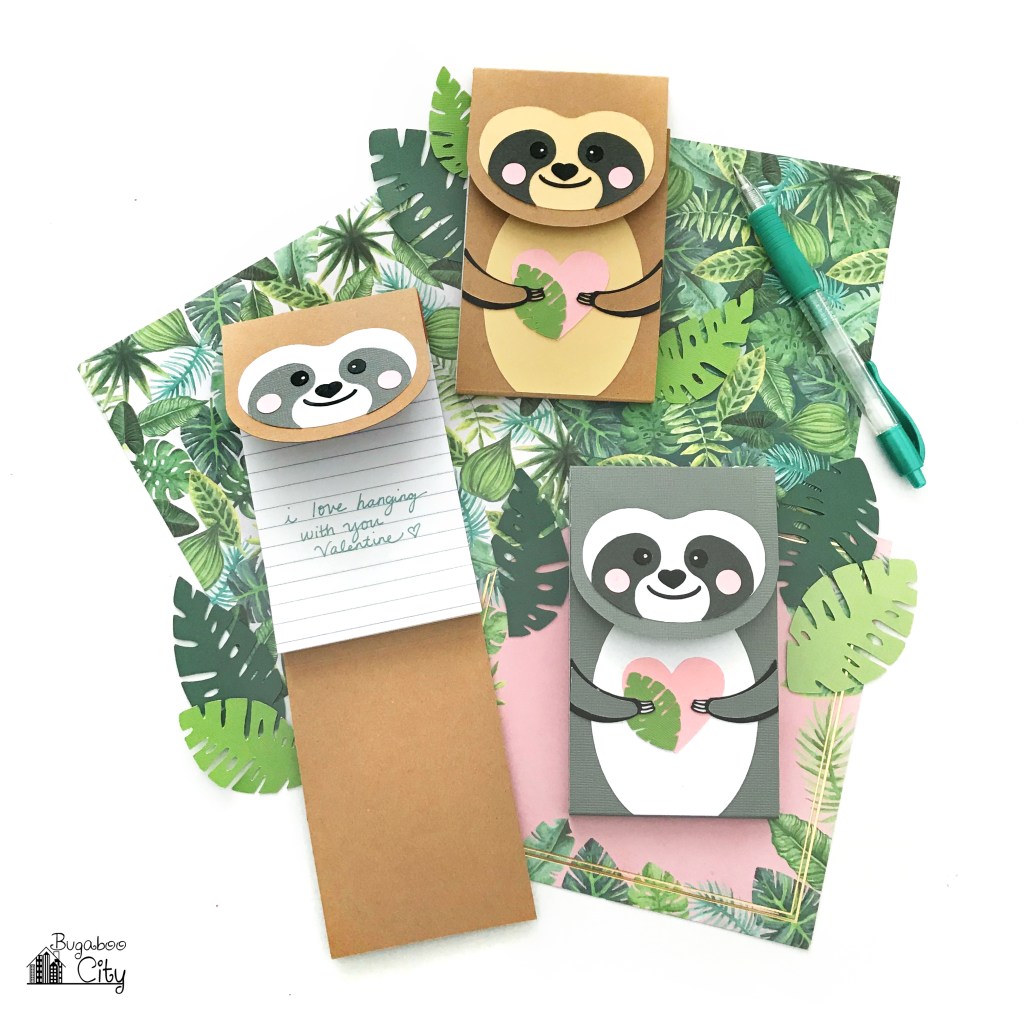 Three kawaii sloth notepads on tropical plant paper on a white background