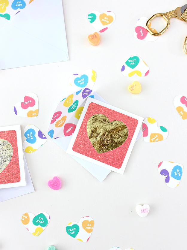 White background with a glittery heart card and conversation heart cut out paper